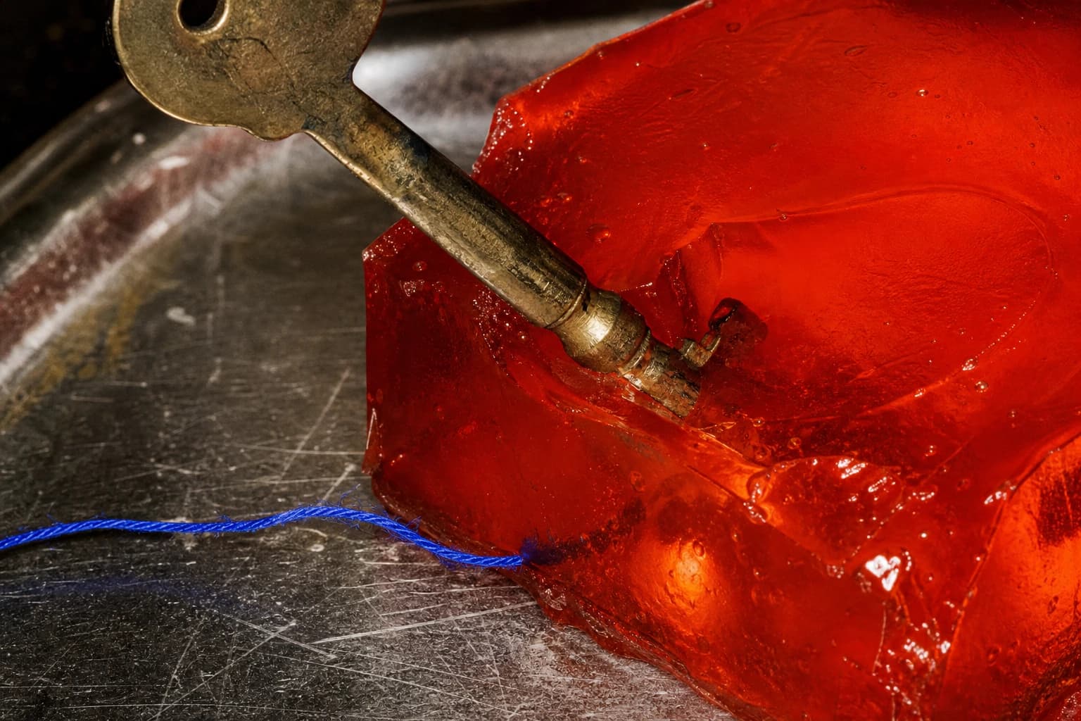 An old brass key embedded in scarlet gelatin